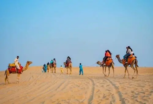 A scenic sunset camel safari traversing the golden dunes of the Thar Desert, a premier adventure featured in our Jaisalmer day trips.