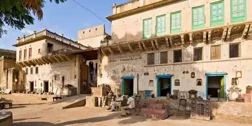The beautifully preserved grand courtyard of a traditional heritage haveli in Mandawa, Shekhawati, adorned with intricate, colorful wall frescoes depicting royal processions and mythological scenes.
